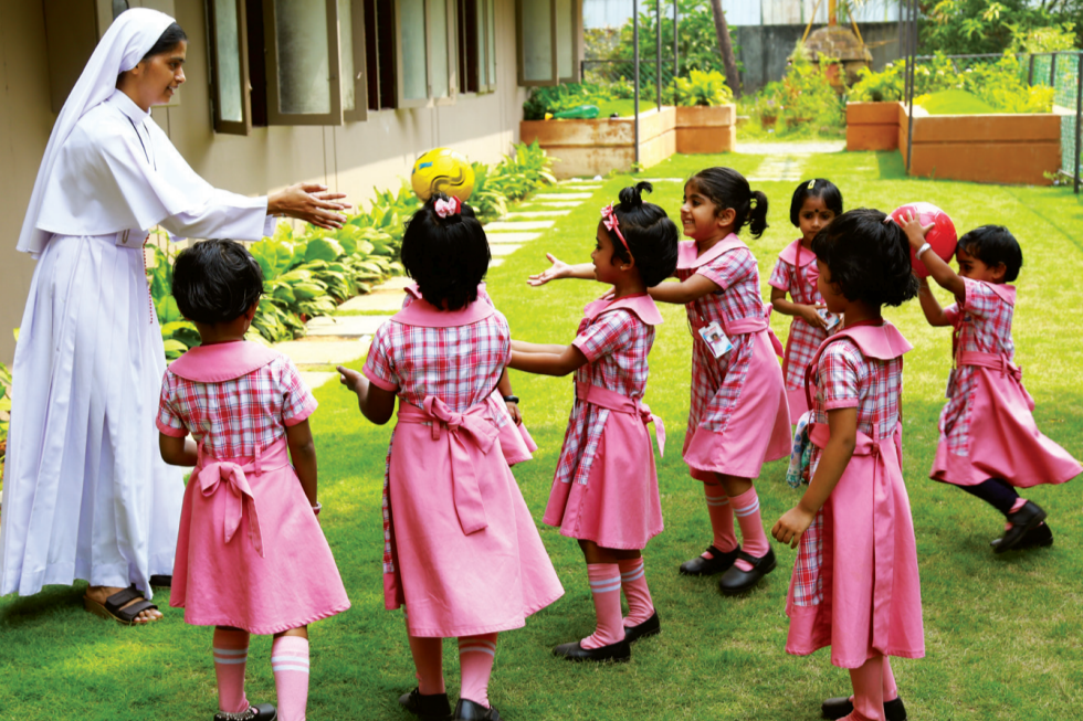 A teacher with kindergarten children on the school lawn